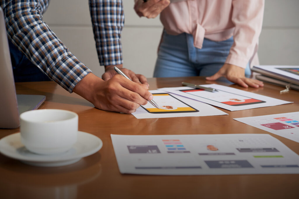 TP CDA - Vue sur le côté, un homme et une femme qui travaillent, crayon à la main, des feuilles imprimées éparpillées sur le bureau