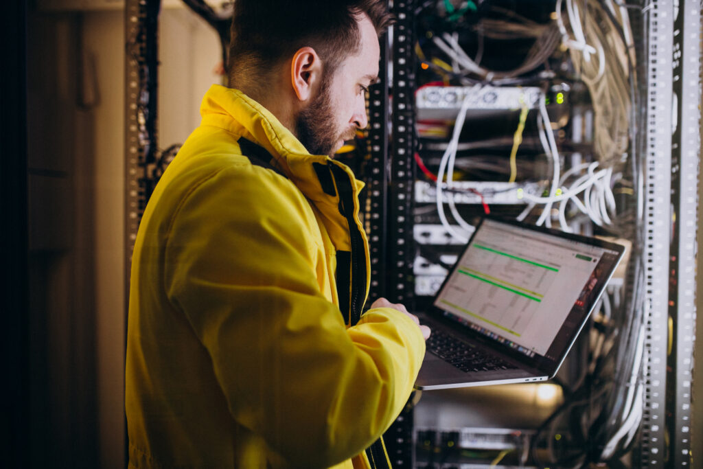 TP TSSR - Jeune homme debout qui tient un ordinateur portable connecté à des serveurs