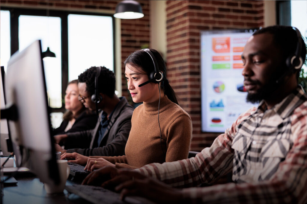 TP Technicien d'Assistance en Informatique - Deux hommes et deux femmes assis devant des ordinateurs, micro-casque sur les oreilles