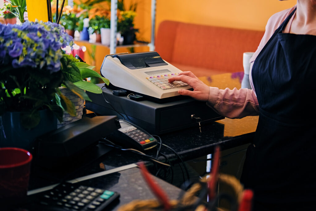 TP Employé Commercial - Femme qui pianote sur une caisse enregistreuse dans un petit commerce de fleurs