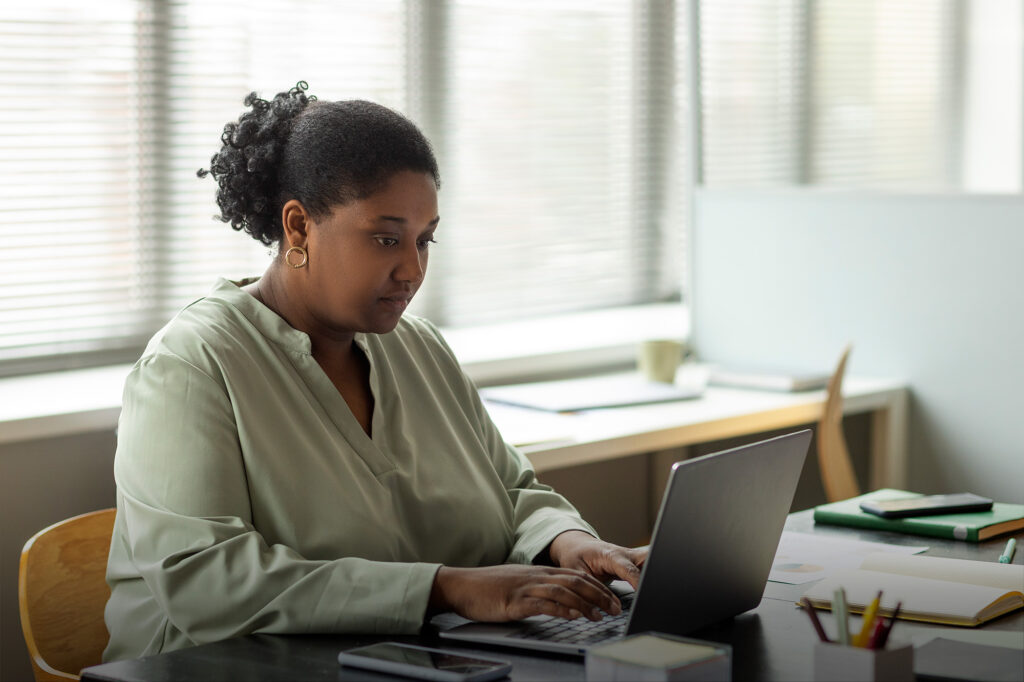 TP SA - femme de face assise à un bureau travaillant sur un ordinateur portable