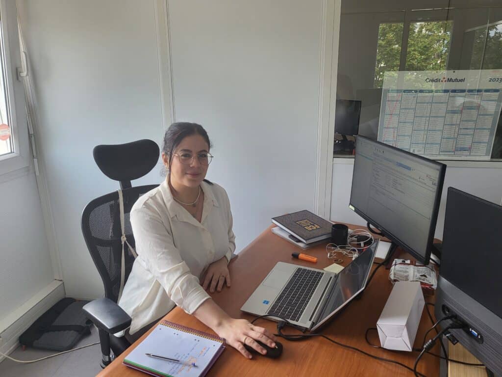 Nadia BOUCHAMA assise à son bureau devant son ordinateur