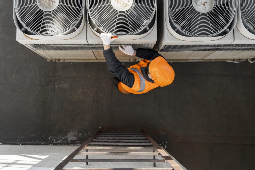 TP AMECC - homme avec un casque orange travaillant sur un équipement de confort climatique