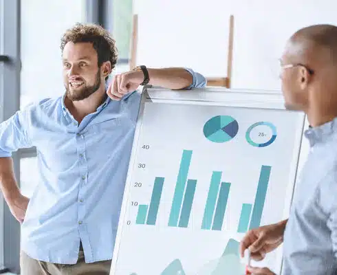 Deux personnes devant un tableau avec graphiques (histogramme, diagramme circulaire) pour le Bachelor Responsable de Développement Commercial